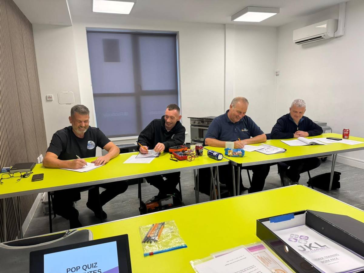 Trainees completing a written assessment on the oven repair course